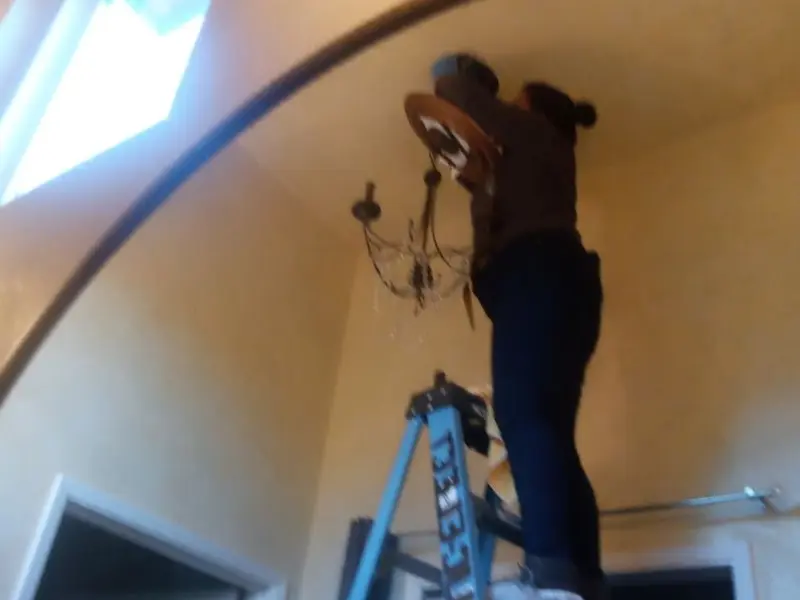 Electrician installing a chandelier in a Carver residence